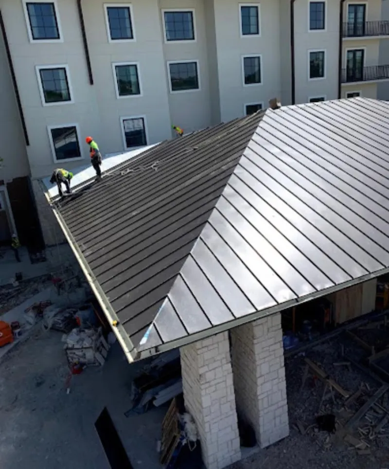 Crew installing standing seam metal roof panels on a commercial project in Linwood